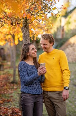 Un couple regarde un téléphone portable sous un arbre aux couleurs d'automne