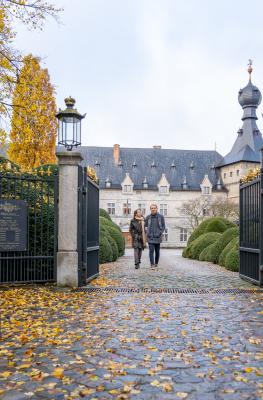 A couple walks by the Chimay castle in autumn