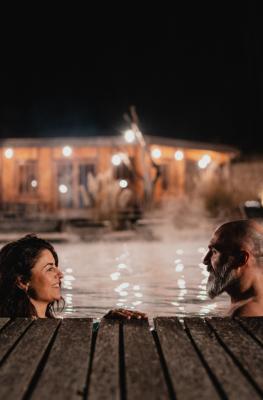 Een koppel 's avonds aan het zwemmen in het verwarmde buitenzwembad van het Domaine de Ronchinne tijdens de winter