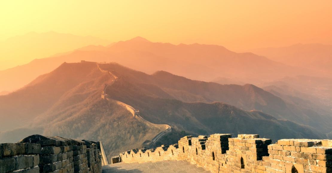 Photo de la muraille de Chine sous un soleil couchant.