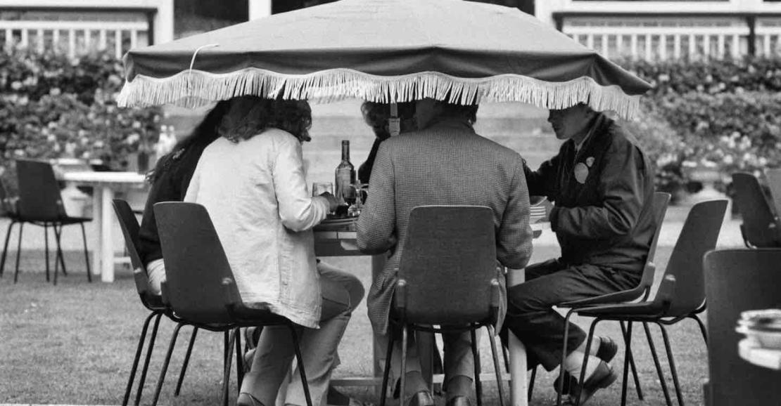 Mensen lunchen in de tuin onder een lage parasol