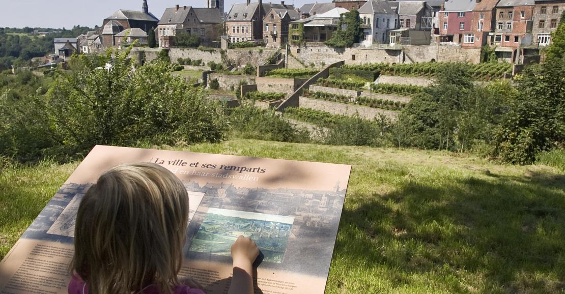 Child from behind reading an explanatory panel facing the panorama of Thuin's hanging gardens